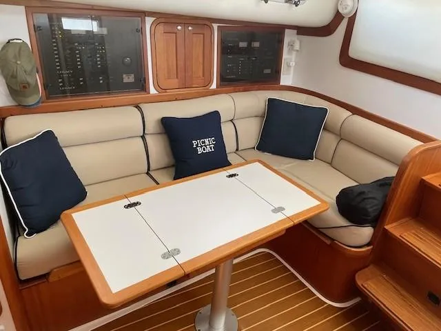 Slide: The Image of 2003 Legacy Yachts 34 Sedan interior with beige seating, wooden accents, and a foldable table. - 46