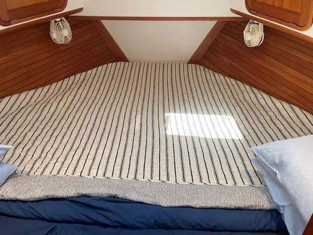 Slide: The Image of Cozy cabin bed in 2003 Legacy Yachts 34 Sedan with striped bedding and wooden accents. - 49