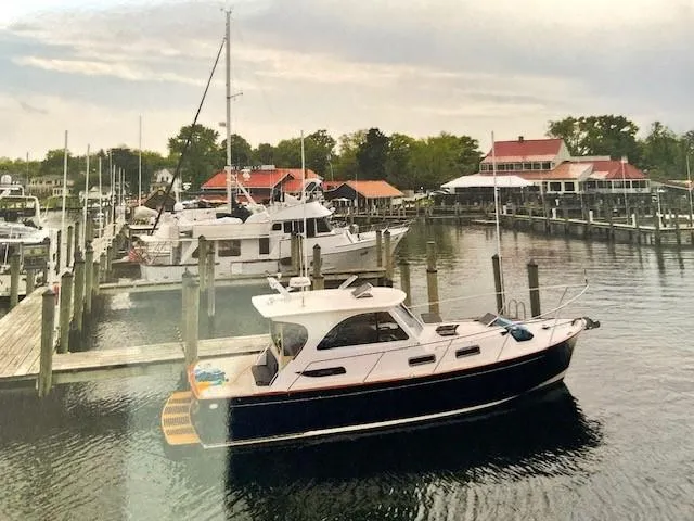 Slide: The Image of 2003 Legacy Yachts 34 Sedan docked in a scenic marina with surrounding boats and buildings. - 8