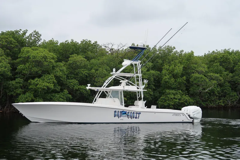 Slide: The Image of 2016 Invincible 42 Open Fisherman boat on calm water near lush greenery. - 2