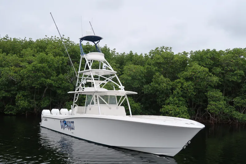 Slide: The Image of 2016 Invincible 42 Open Fisherman boat on calm water near lush greenery. - 5