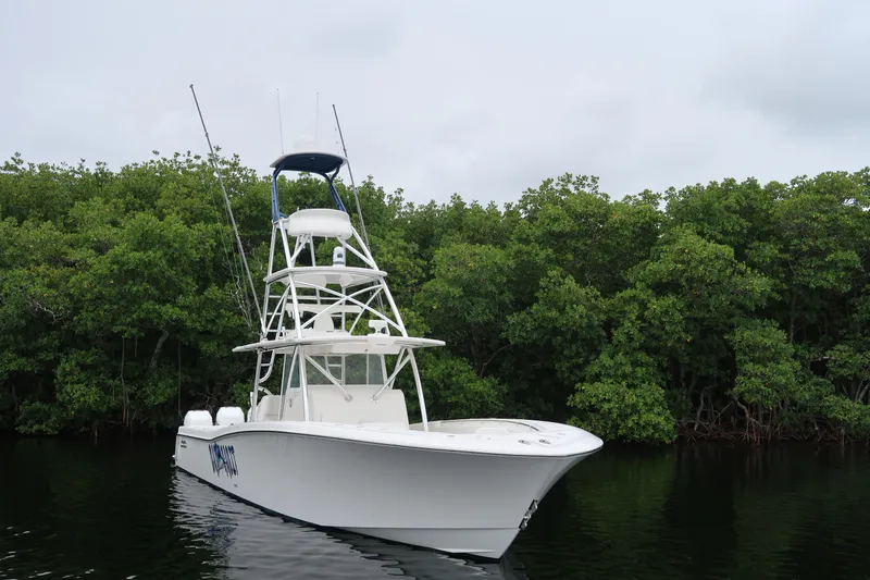 Slide: The Image of 2016 Invincible 42 Open Fisherman boat on calm water near lush greenery. - 6