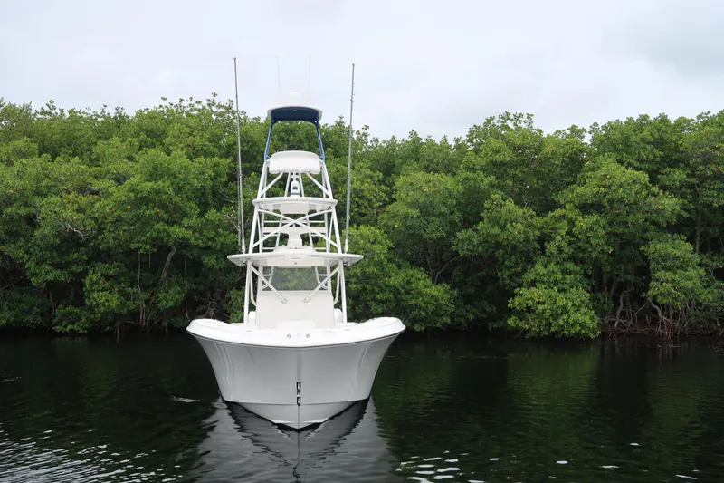 Slide: The Image of 2016 Invincible 42 Open Fisherman boat on calm water with lush green background. - 7