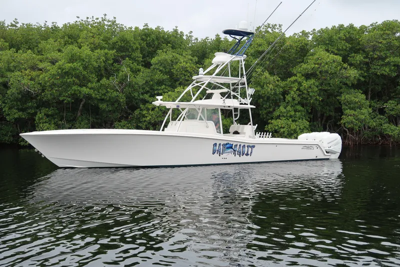 Slide: The Image of 2016 Invincible 42 Open Fisherman boat on calm water near lush greenery. - 8