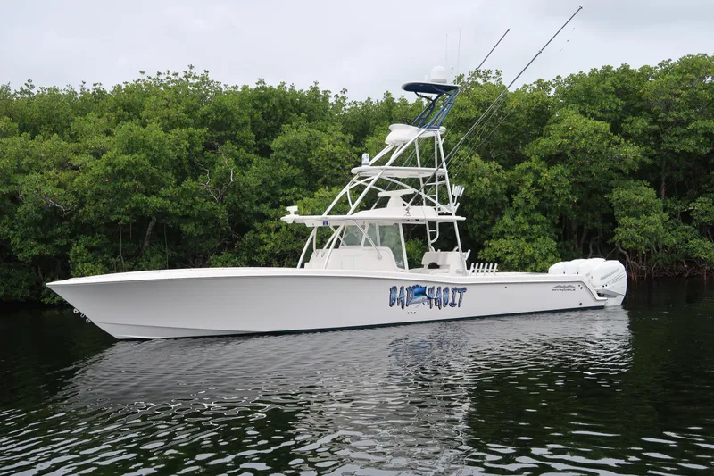 Slide: The Image of 2016 Invincible 42 Open Fisherman boat on calm water near lush greenery. - 9