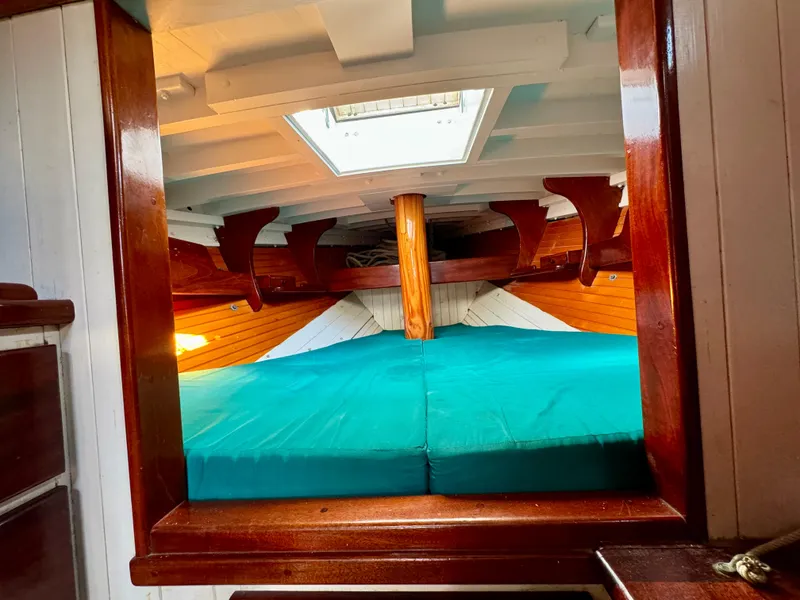 Slide: The Image of Interior of 1996 Custom John Alden Malabar II sailboat with wooden finish and teal bedding. - 32
