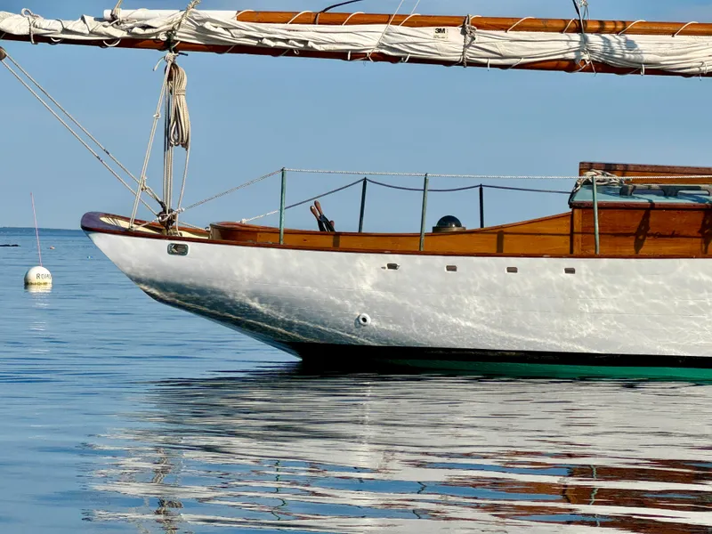 Slide: The Image of Sailboat "John Alden Malabar II" from 1996 on calm water, showcasing classic wooden design. - 9