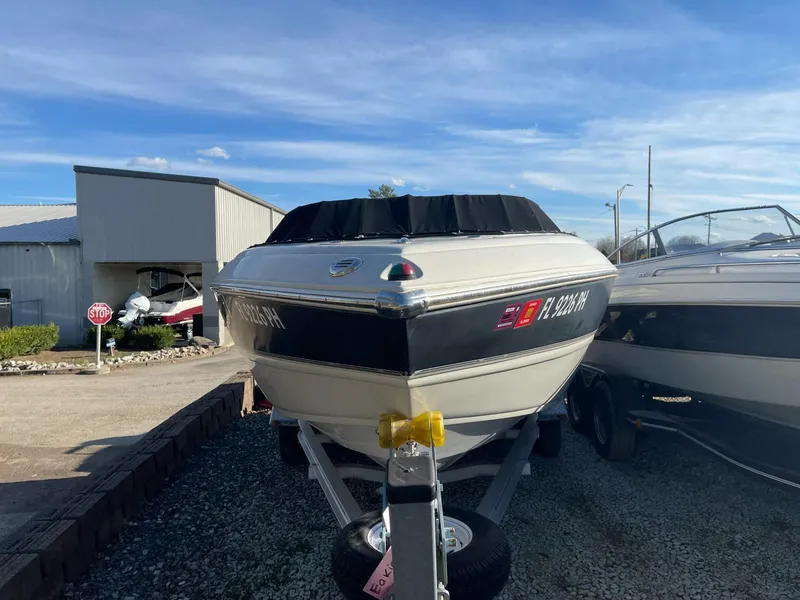 Slide: The Image of 2012 Stingray 225 LR boat on trailer, parked outdoors under clear blue sky. - 10