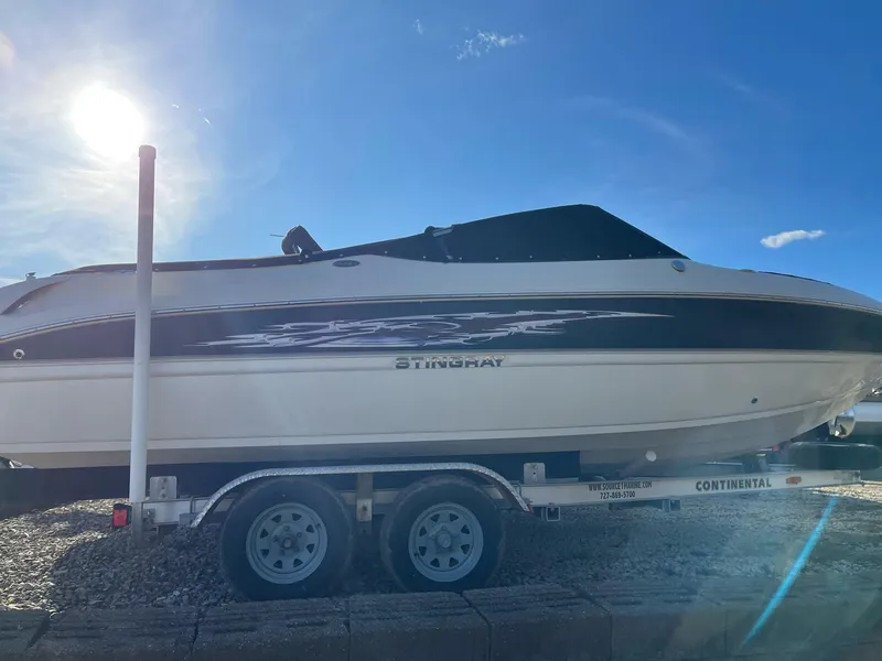 Slide: The Image of 2012 Stingray 225 LR boat on trailer under bright blue sky. - 12