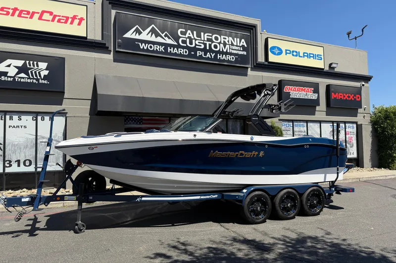 The Image of 2024 MasterCraft X24 boat on trailer outside California Custom showroom. - 0