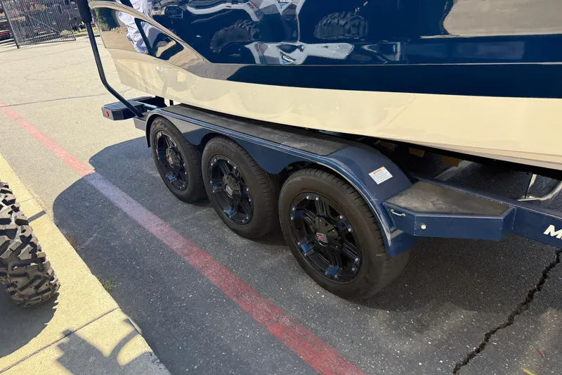 Slide: The Image of 2024 MasterCraft X24 boat on a triple-axle trailer, parked on pavement. - 11