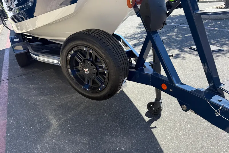 Slide: The Image of 2024 MasterCraft X24 boat trailer with black alloy wheel on pavement. - 12