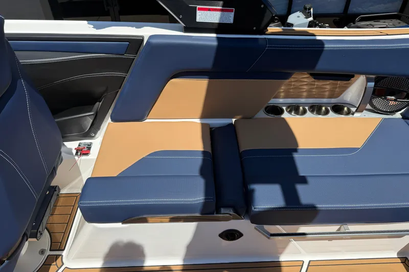 Slide: The Image of 2024 MasterCraft X24 boat interior with blue and tan seating, cup holders, and sleek design. - 17