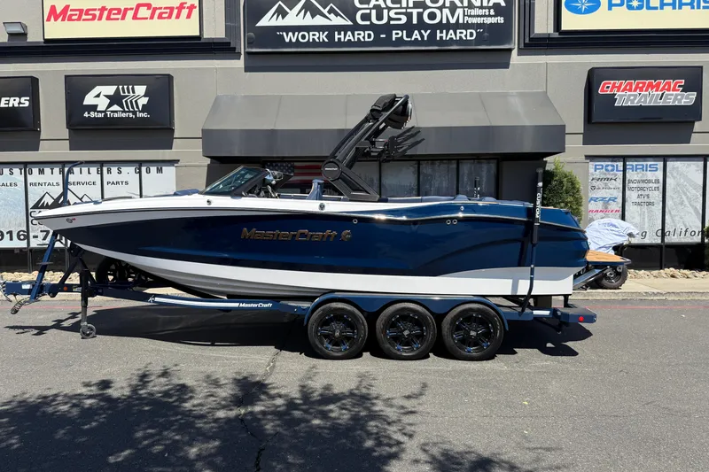 Slide: The Image of 2024 MasterCraft X24 boat on trailer outside dealership, showcasing sleek design and modern features. - 2