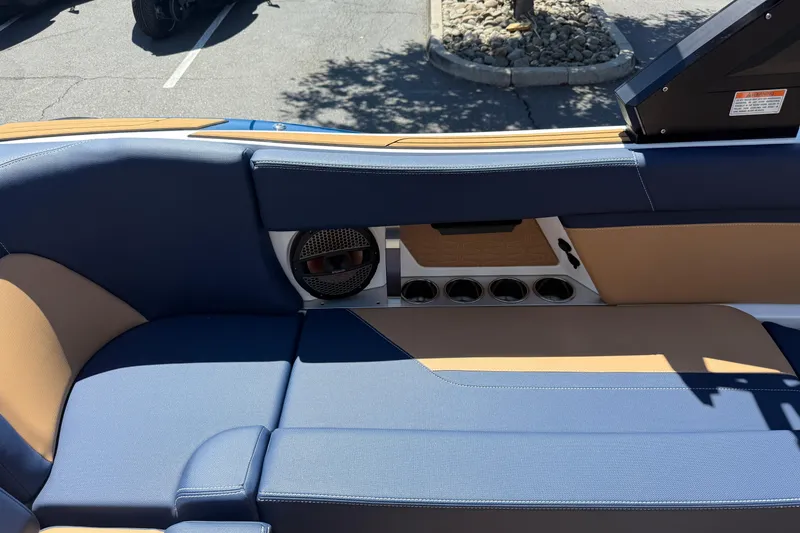 Slide: The Image of 2024 MasterCraft X24 boat interior with blue and tan seating, speaker, and cup holders. - 22
