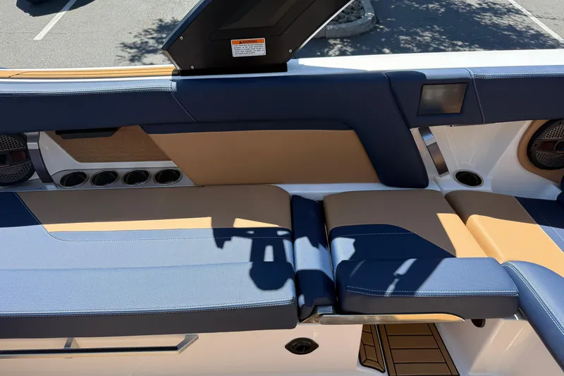 Slide: The Image of 2024 MasterCraft X24 boat interior with blue and tan seating, cup holders, and speakers. - 23