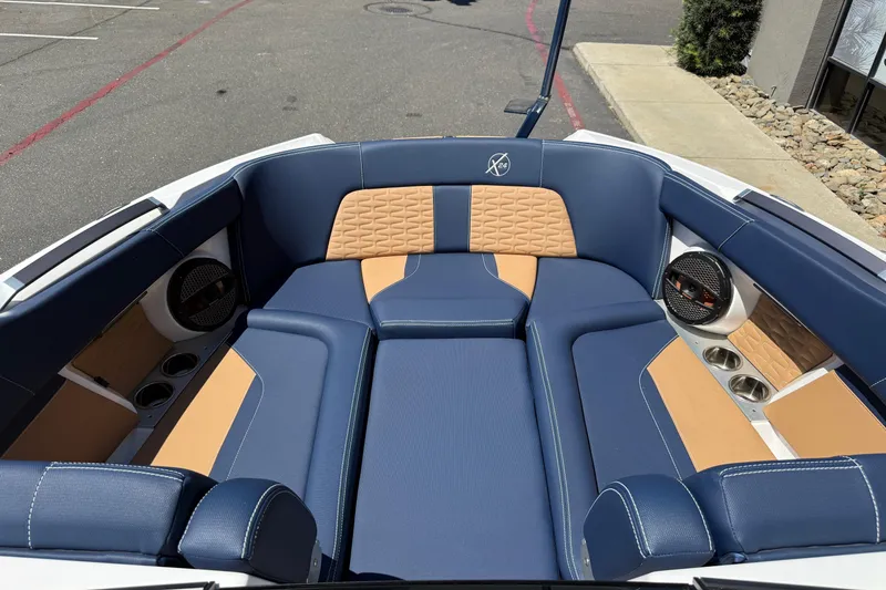 Slide: The Image of 2024 MasterCraft X24 boat interior with blue and tan seating, featuring cup holders and speakers. - 27