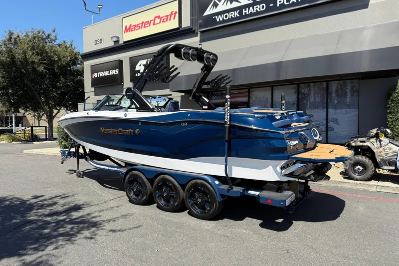 Slide: The Image of 2024 MasterCraft X24 boat on trailer outside dealership, showcasing sleek design and modern features. - 3