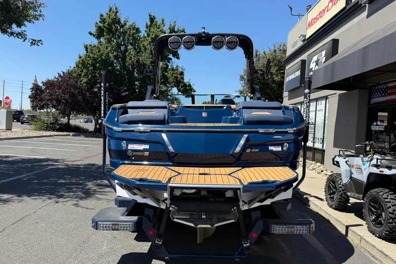 Slide: The Image of 2024 MasterCraft X24 boat, blue exterior, parked outside dealership, rear view. - 4