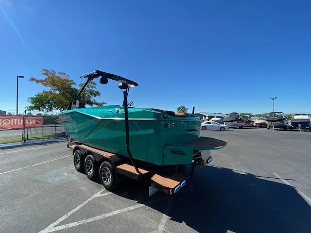 Slide: The Image of 2022 Axis Wake Research T250 boat on trailer in parking lot under clear blue sky. - 5
