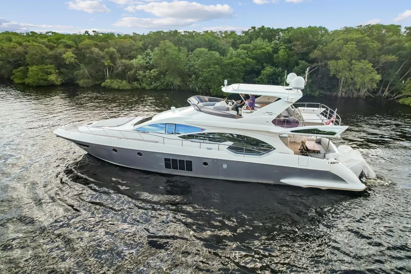 Slide: The Image of 2013 Azimut 70 yacht cruising on a serene river with lush green trees. - 29