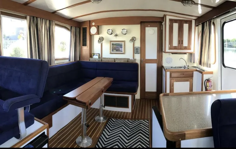 Slide: The Image of Interior of 2007 Duffy Aft Cabin with blue seating, wooden accents, and kitchenette. - 19