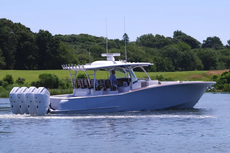 Slide: The Image of 2025 Mag Bay 43 CC boat cruising on a lake with lush green background. - 11