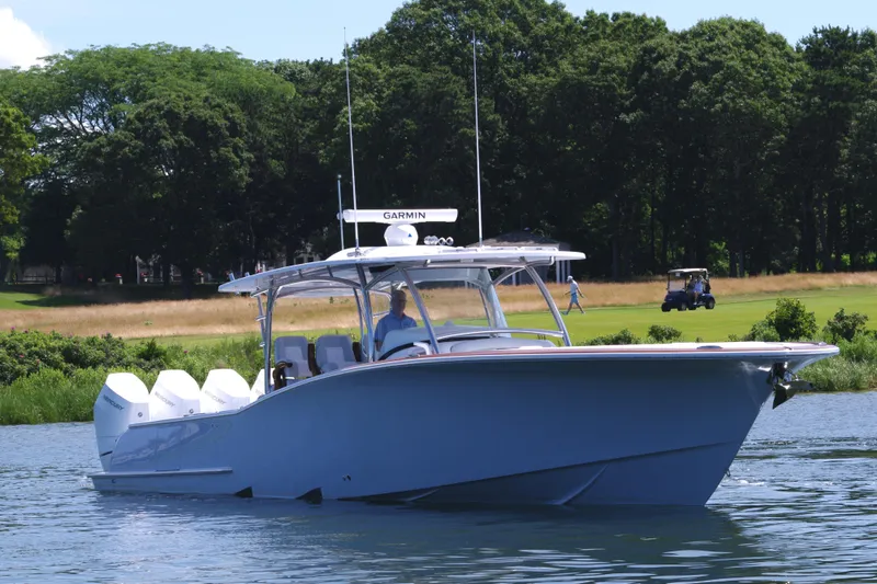 Slide: The Image of 2025 Mag Bay 43 CC boat on a calm lake with lush greenery. - 13