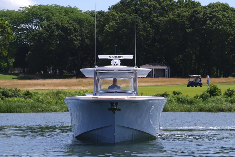 Slide: The Image of 2025 Mag Bay 43 CC boat cruising on a calm lake with lush greenery in the background. - 16