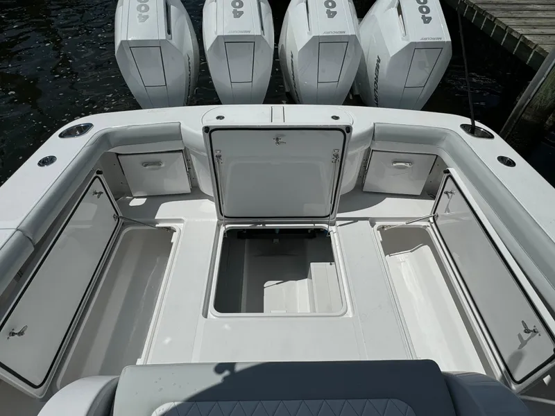 Slide: The Image of 2025 Mag Bay 43 CC boat with open storage compartments and four outboard engines. - 26