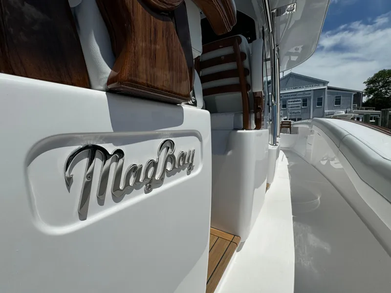 Slide: The Image of 2025 Mag Bay 43 CC boat exterior with logo and wooden accents. - 39