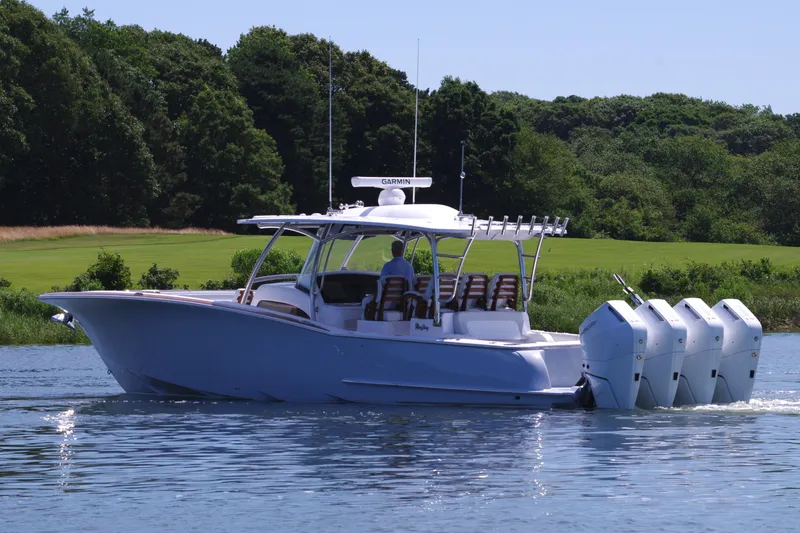 Slide: The Image of 2025 Mag Bay 43 CC boat cruising on a lake with lush green background. - 4