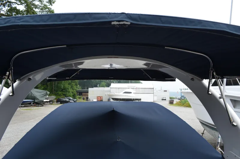 Slide: The Image of 2013 Four Winns H310 boat with blue canvas cover and arch, docked in a marina. - 13