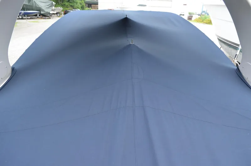 Slide: The Image of 2013 Four Winns H310 boat with a blue cover in a storage area. - 14