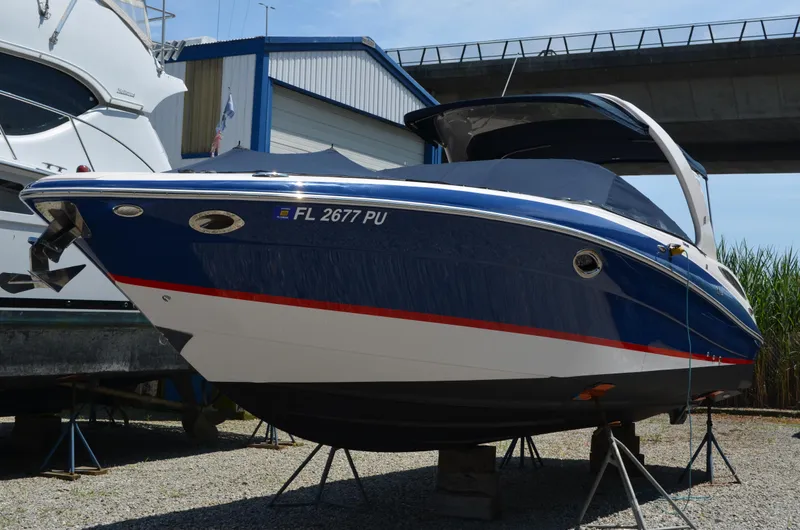 Slide: The Image of 2013 Four Winns H310 boat on stands, blue and white hull, docked near a bridge. - 3
