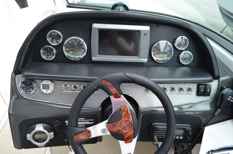 Slide: The Image of 2013 Four Winns H310 boat dashboard with steering wheel, gauges, and Garmin GPSmap 740. - 35