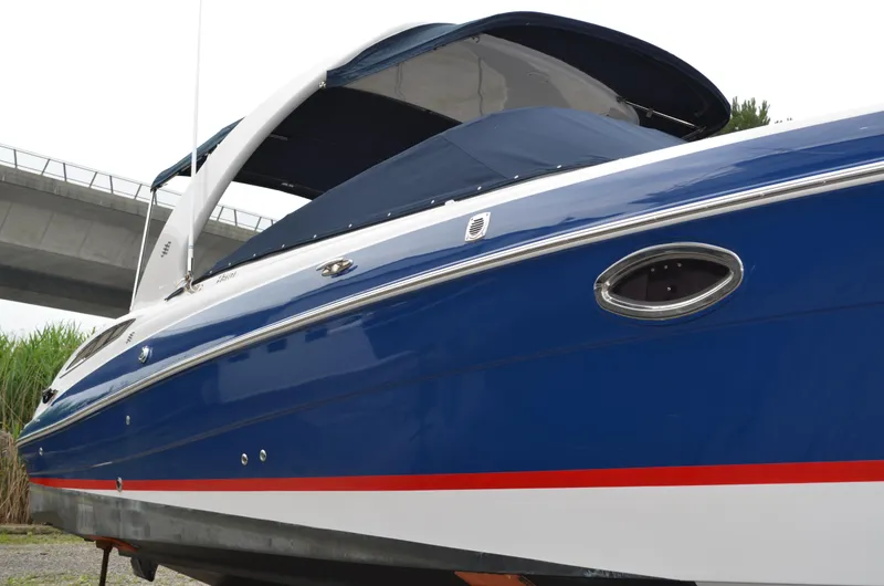 Slide: The Image of 2013 Four Winns H310 boat with blue hull and red stripe under a bridge. - 4