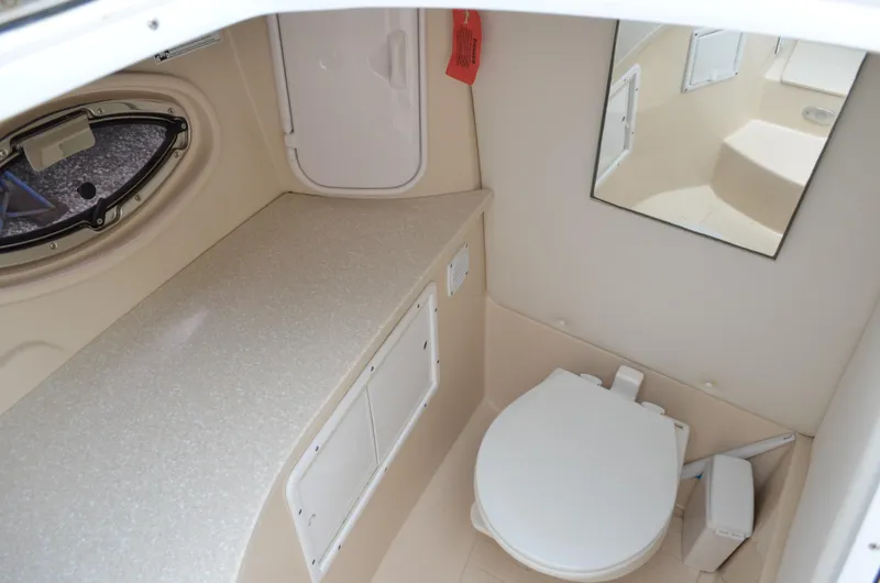 Slide: The Image of 2013 Four Winns H310 boat bathroom with toilet, countertop, mirror, and porthole window. - 47