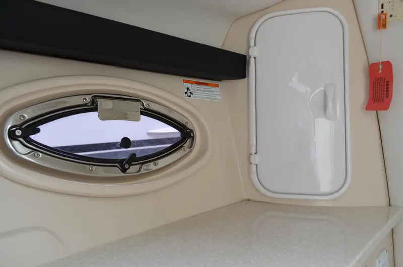 Slide: The Image of Interior of 2013 Four Winns H310 boat showing a porthole and storage compartment. - 49