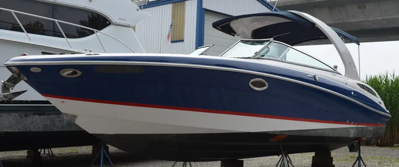 Slide: The Image of 2013 Four Winns H310 boat on stands, blue and white hull with red stripe. - 5