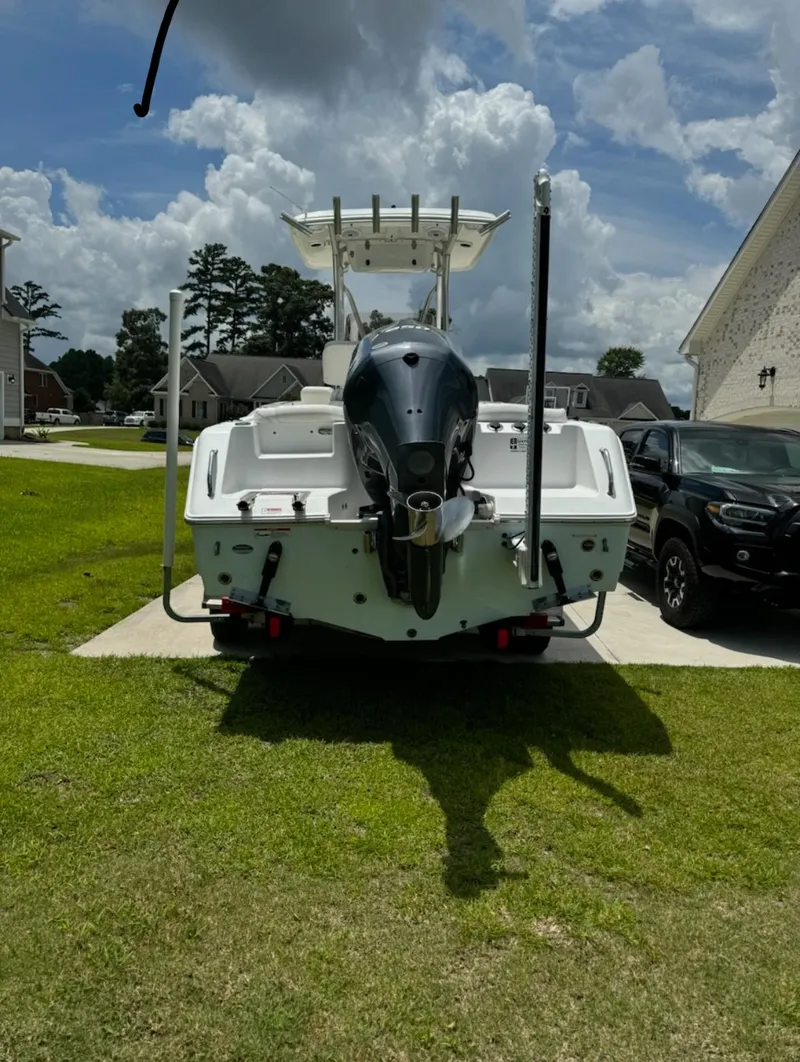 Slide: The Image of 2016 Sea Hunt Ultra 234 boat parked on a driveway under a cloudy sky. - 1