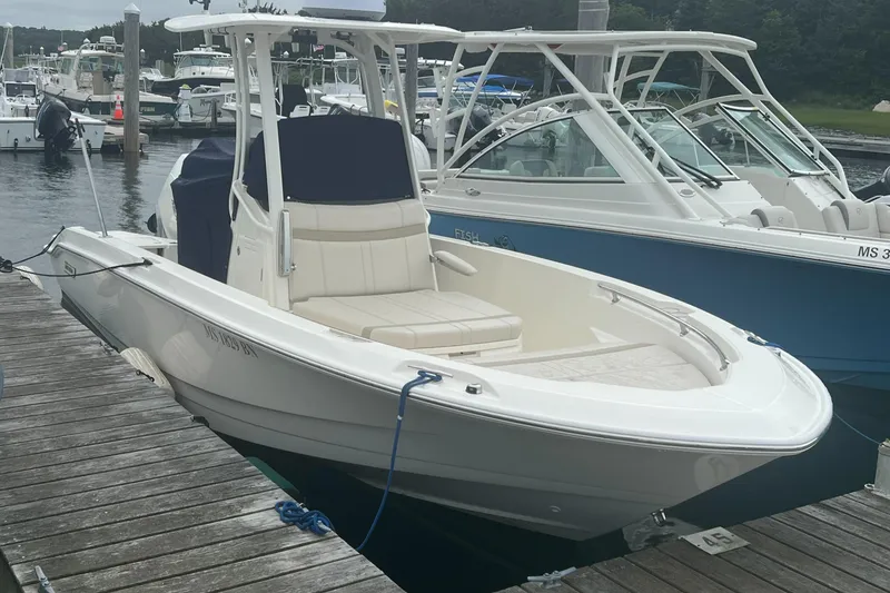 Slide: The Image of 2025 Boston Whaler 220 Dauntless boat docked at marina, featuring sleek design and spacious seating. - 0