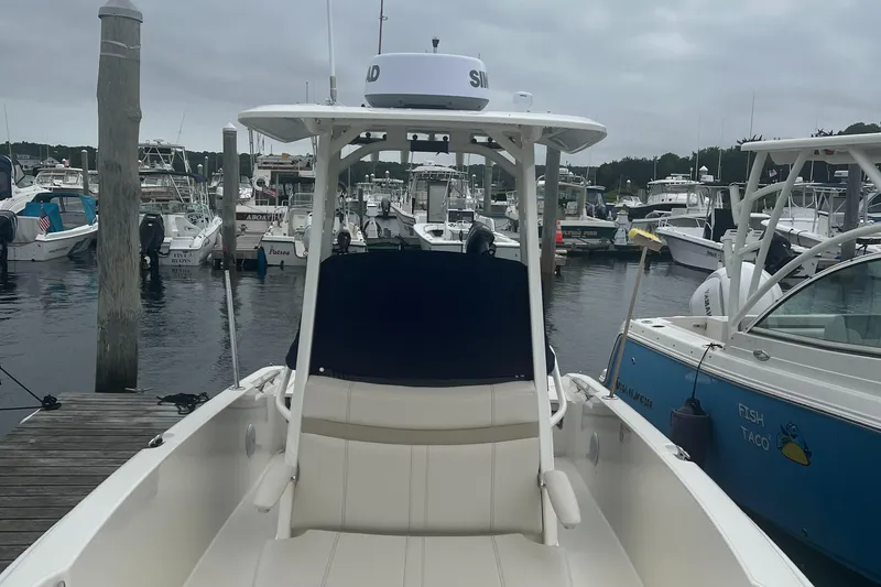 Slide: The Image of Boston Whaler 220 Dauntless 2025 docked at marina, surrounded by other boats. - 2