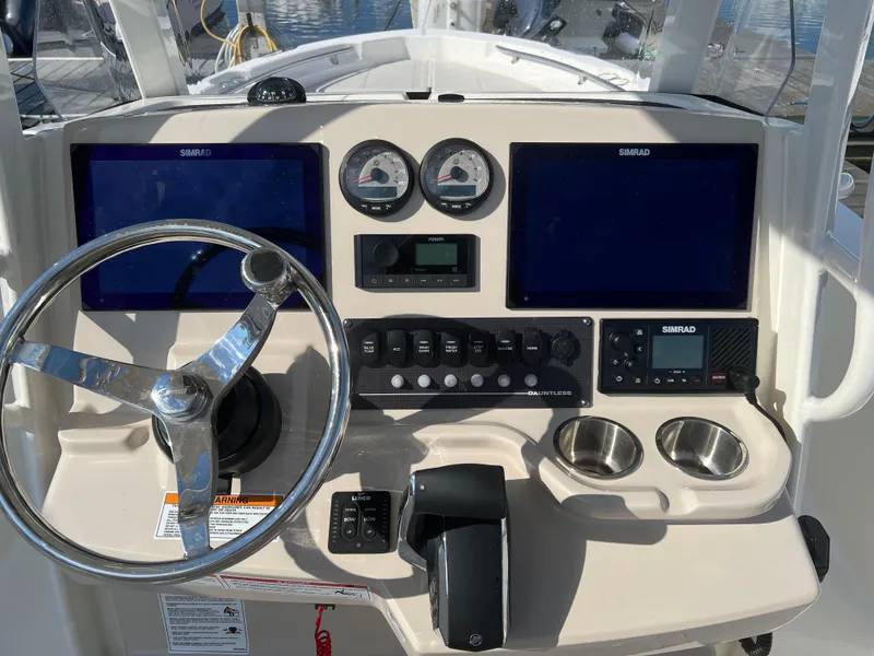 Slide: The Image of 2024 Boston Whaler 220 Dauntless boat dashboard with steering wheel and navigation screens. - 5
