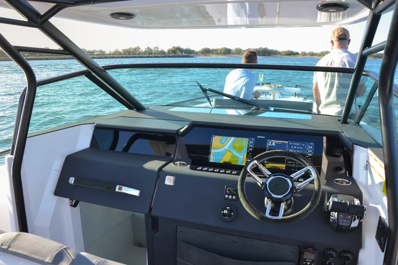 Slide: The Image of 2024 Axopar 37 Sun Top boat interior with modern dashboard and steering wheel. - 4