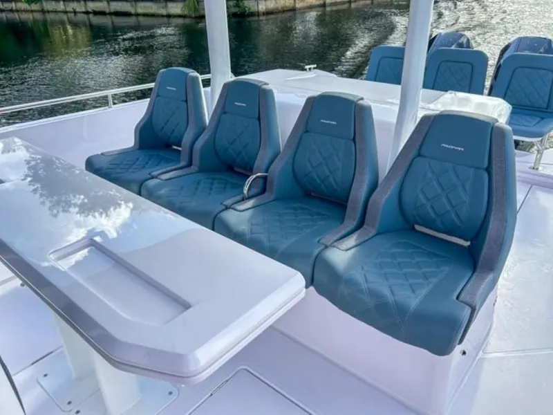 Slide: The Image of 2024 Axopar 37 Sun Top boat with luxurious blue seating and sleek white table. - 17