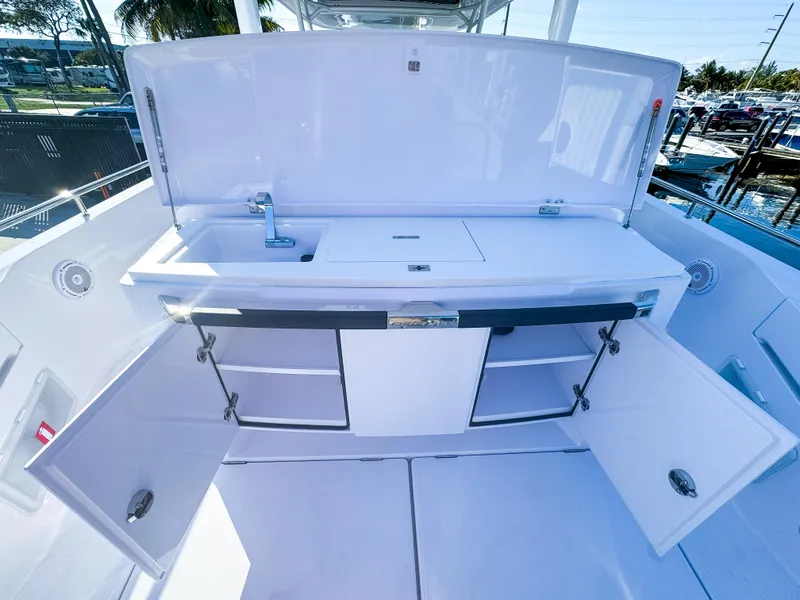 Slide: The Image of 2024 Axopar 37 Sun Top boat kitchen area with sink and storage cabinets. - 8