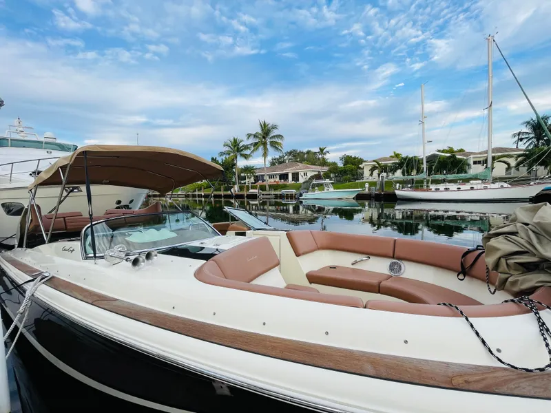 Slide: The Image of 2014 Chris-Craft Launch 32 boat docked in a marina with palm trees and houses in the background. - 10