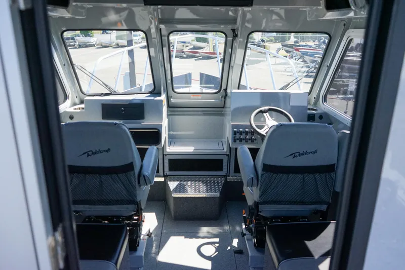 Slide: The Image of Interior of 2025 Weldcraft 240 Ocean King boat with dual captain chairs and control panel. - 5