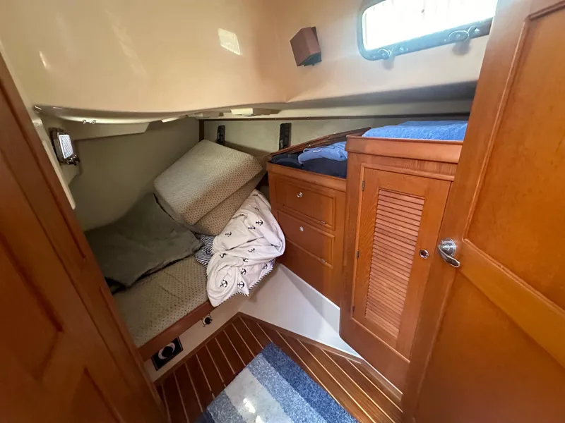 Slide: The Image of 2002 Island Packet 420 cabin interior with bed and wooden storage cabinets. - 23